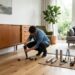 Personne améliorant sa déco avec un pied de meuble dans un salon moderne lumineux