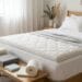 Surmatelas blanc moelleux choisi sur un lit avec échantillons de mousse à côté