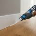 Mains comblant l’espace entre une plinthe et un parquet
