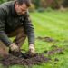 Jardinier posant un piège à taupe métallique dans une taupinière sur pelouse verte