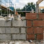 Mur en construction comparant côte à côte des blocs de parpaing et des briques en terre cuite