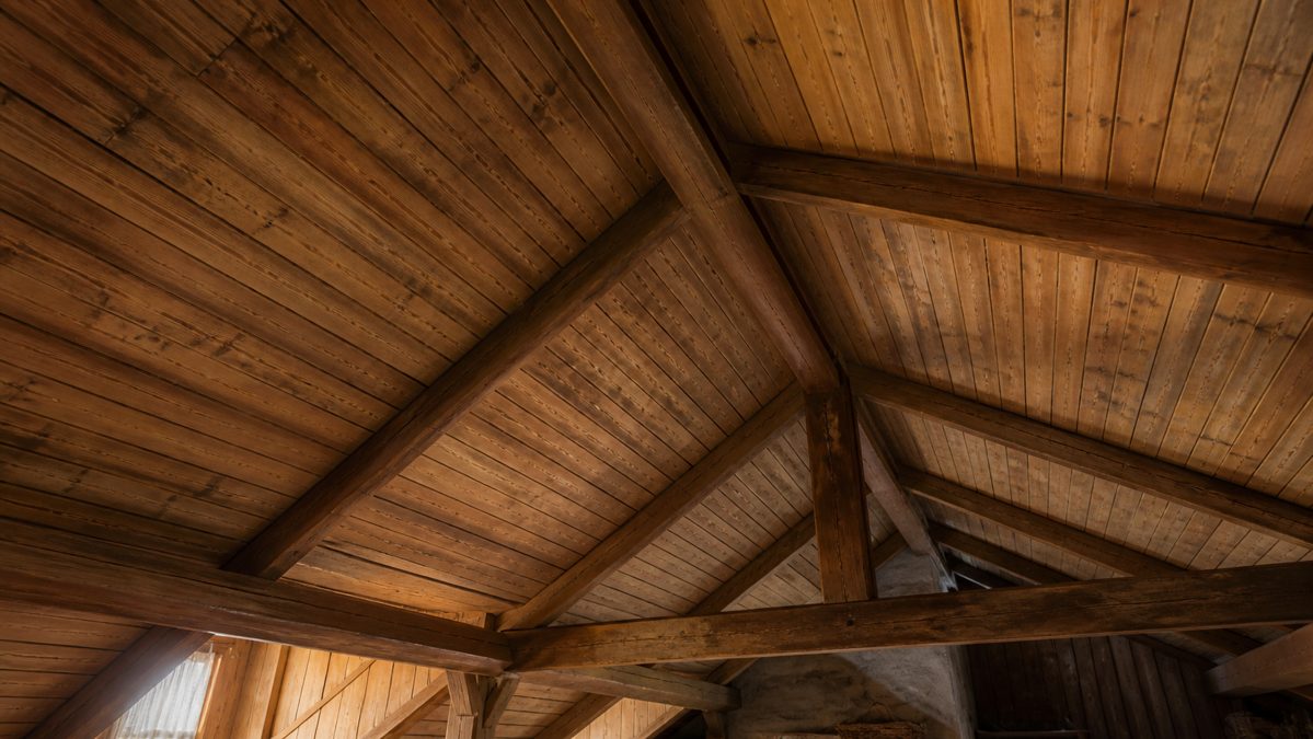 Plafond en lambris ancien avant rénovation Ancien plafond en lambris de bois brut dans des combles aménagés