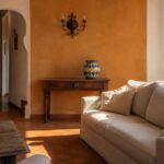 Salon style sicilien mur ocre céramique Salon inspiré du style sicilien avec mur ocre, canapé lin et vase en céramique peinte
