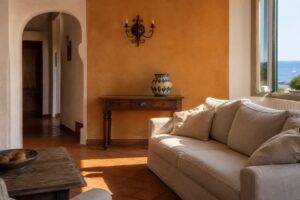 Salon inspiré du style sicilien avec mur ocre, canapé lin et vase en céramique peinte