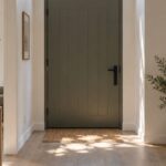 Entrée de maison avec porte moderne surmontée d'une imposte vitrée qui laisse entrer la lumière naturelle