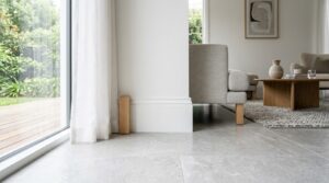 Plinthe en bois peinte en blanc sur un sol carrelé gris clair dans un salon lumineux