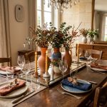 Table de fête avec surtout de table moderne Table de fête avec plateau miroir, vases en céramique terracotta et bleue et bougies dans un salon