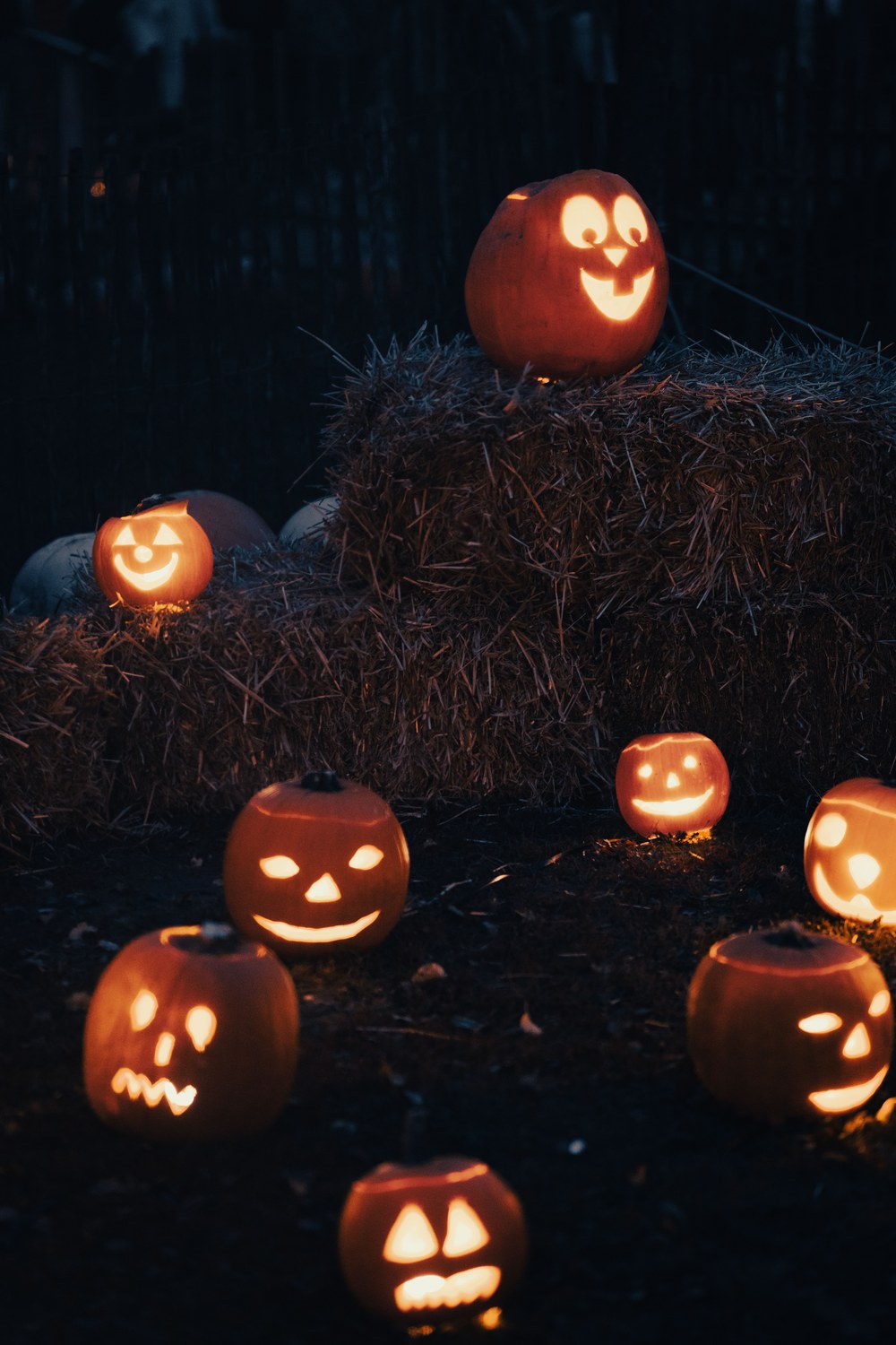 Citrouilles sculptées éclairées de l'intérieur posées sur des bottes de paille la nuit