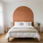 Chambre claire avec une arche terracotta peinte au mur derrière un lit double
